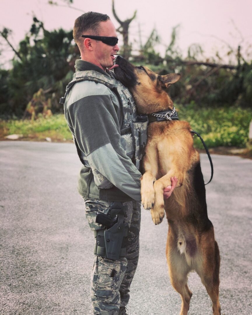 Military man hugs his German Shepherd.