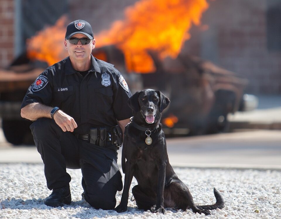 San Antonio arson investigator with a Fire K9 in front of a controlled burn.