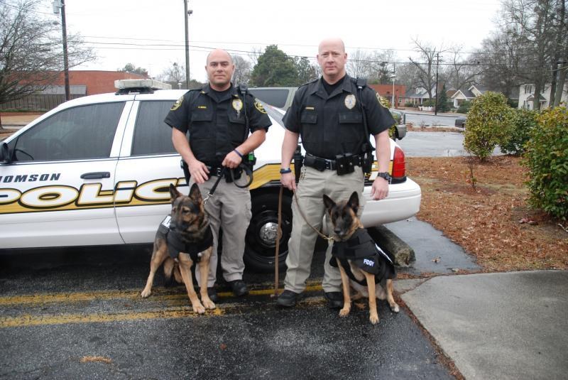 Two Thomson, GA Police K9 officers with K9 Fredy and K9 Fidgy beside their patrol car