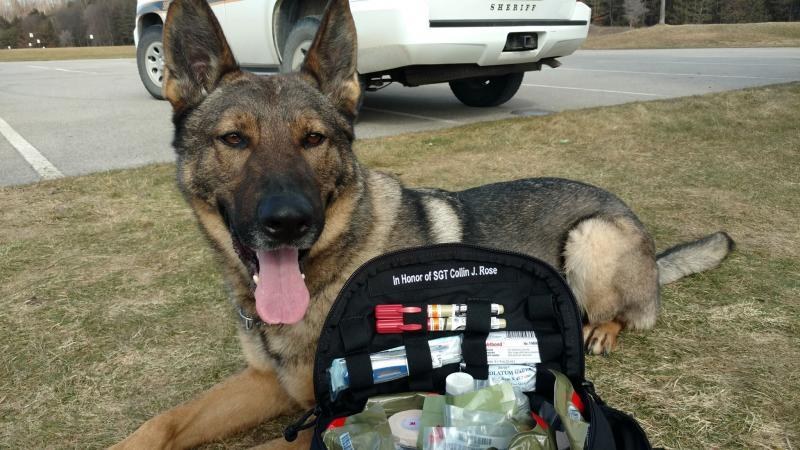 K9 trauma kit inscribed in honor of SGT Collin J. Rose beside a Military Police vehicle